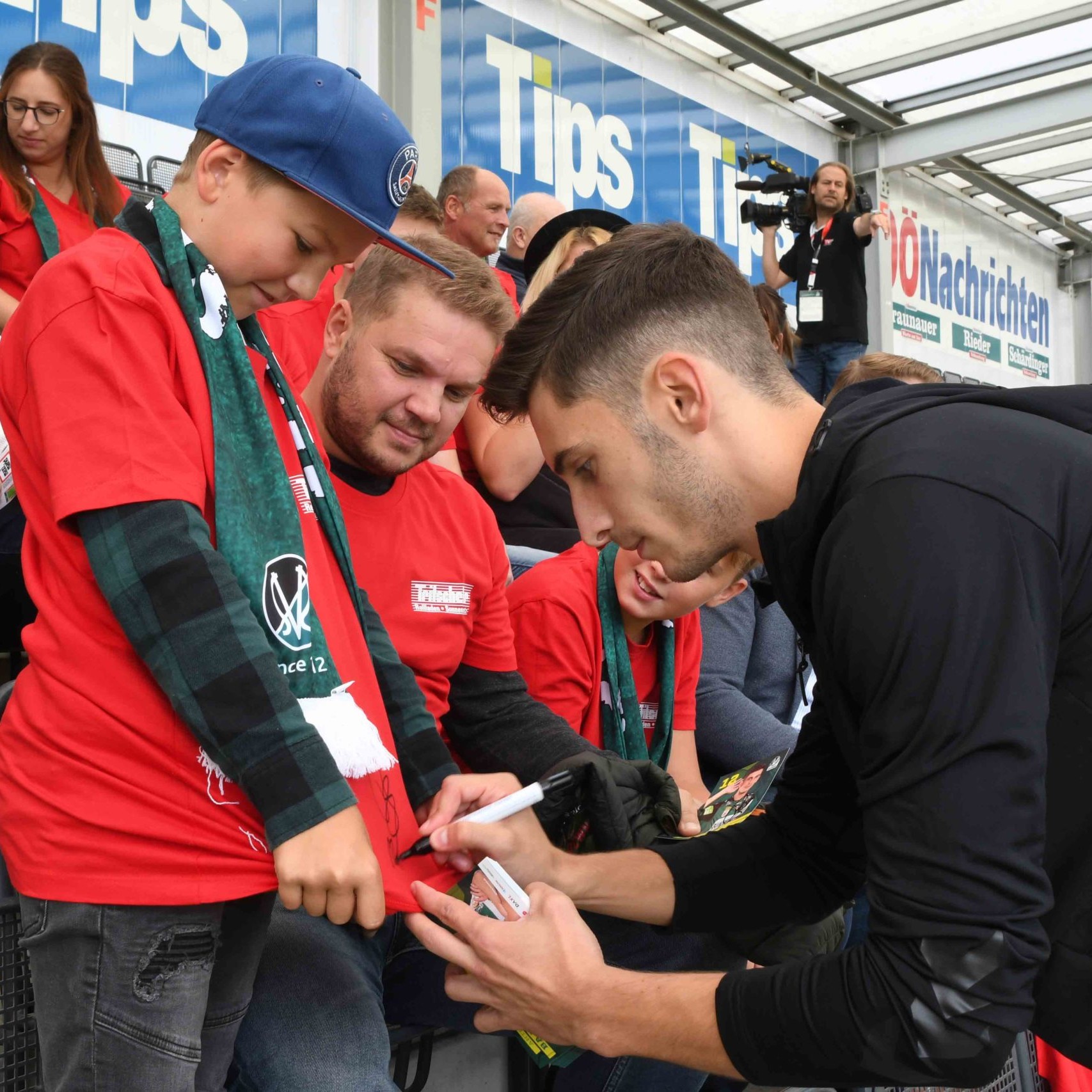 Spieler unterschreibt beim Kind auf Shirt